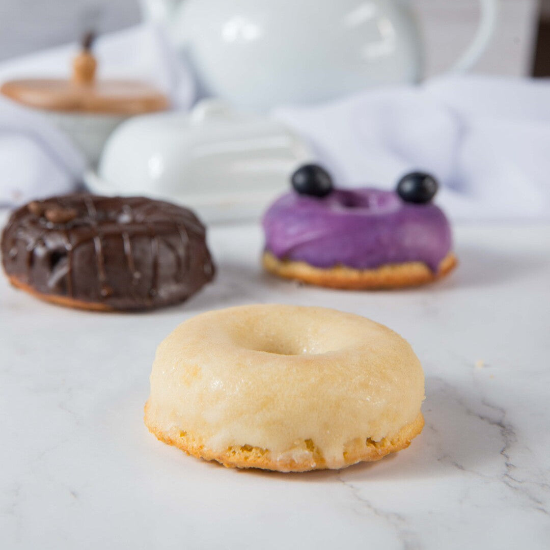 Three FITbelly donuts on a marble surface with a teapot in the background