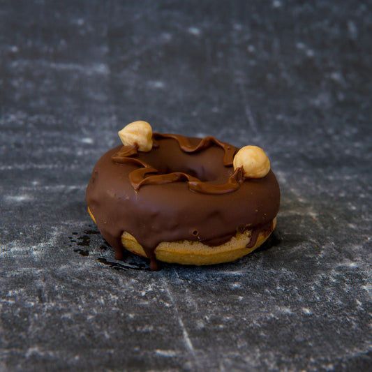 Chocolate-glazed FITbelly donut with nuts on a textured black surface