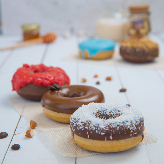 Assorted FITbelly donuts with different toppings on a wooden surface.