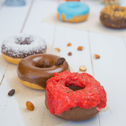 Assorted FITbelly donuts with different flavors on a light wooden surface.